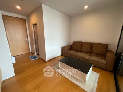 Cozy living room with brown leather sofa and wooden flooring, perfect for relaxation.