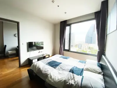 Modern bedroom with large window offering stunning city view in high-rise apartment.