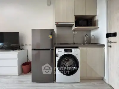 Modern kitchen with stainless steel fridge, washing machine, and microwave in compact layout.