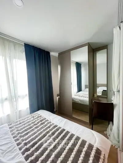 Cozy bedroom with modern decor and ample natural light, featuring a stylish wardrobe and elegant curtains.