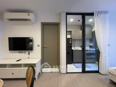 Modern studio apartment with sleek kitchen and wall-mounted TV