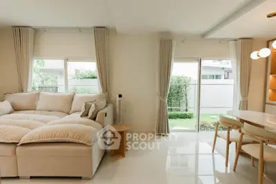 Modern living room with plush sofa and garden view, featuring elegant dining area and natural light.