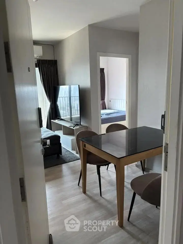 Modern apartment interior with dining area and living room featuring sleek furniture and natural light.