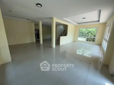 Spacious open-plan living room with large windows and glossy tiled floors