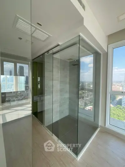 Modern bathroom with glass shower and city view in high-rise apartment.