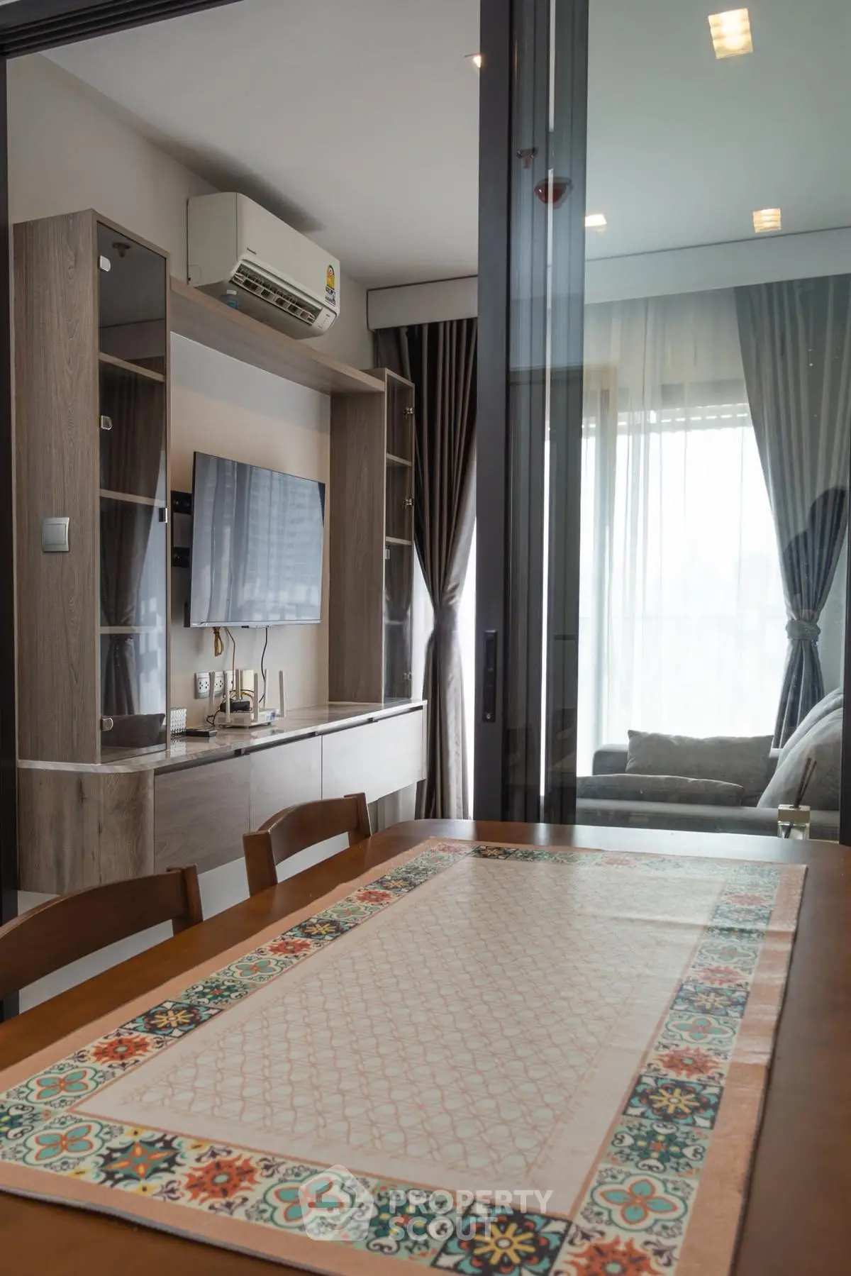Modern living room with stylish decor and air conditioning, featuring a cozy dining area and elegant curtains.