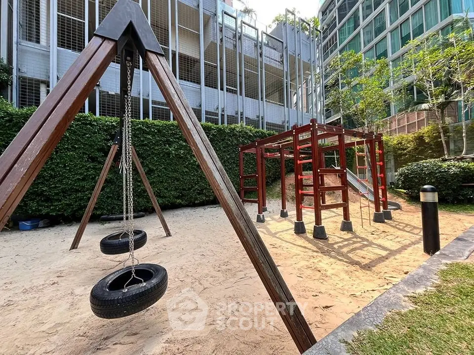 Modern playground area in a residential complex with swings and climbing structures.