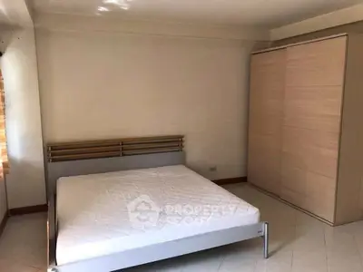 Spacious bedroom with minimalist design featuring a large wardrobe and natural light.