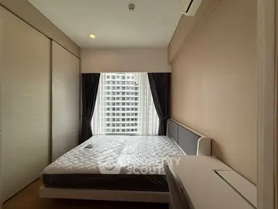 Modern bedroom with large window and city view, featuring a comfortable bed and sleek design.