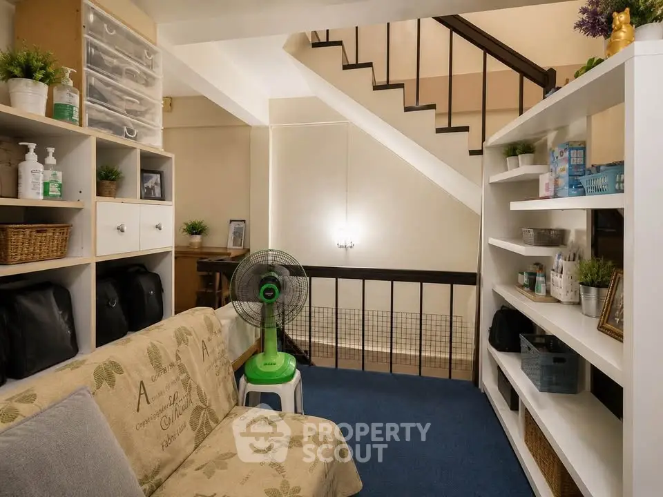 Cozy living room with staircase, shelves, and sofa in a well-organized home interior.