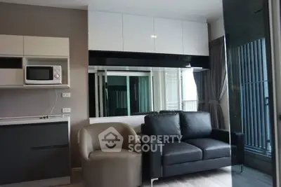 Modern living room with sleek furniture and kitchenette in a stylish apartment.