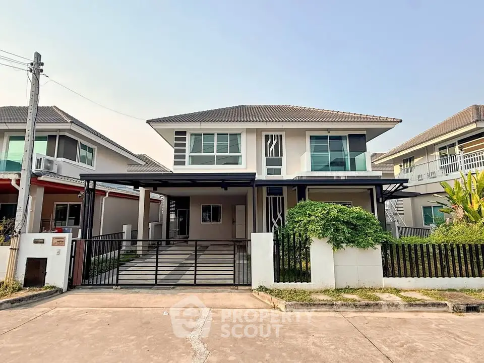 Modern two-story house with gated driveway and lush greenery in a suburban neighborhood.