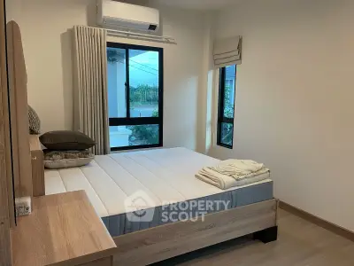 Cozy bedroom with modern furnishings and large windows offering natural light.