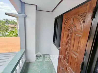 Charming balcony with ornate wooden door and green tiled floor, perfect for relaxation.