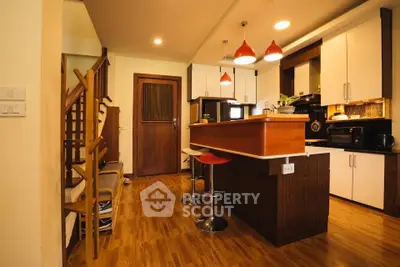 Modern kitchen with wooden flooring and stylish bar stools in a cozy home setting.