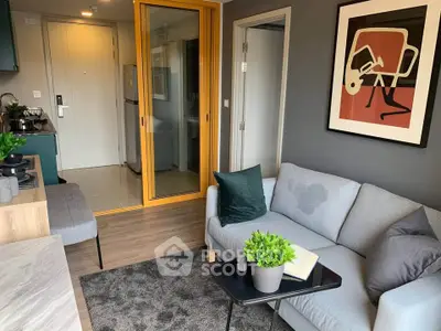 Modern living room with stylish decor and open kitchen layout, featuring cozy seating and vibrant artwork.