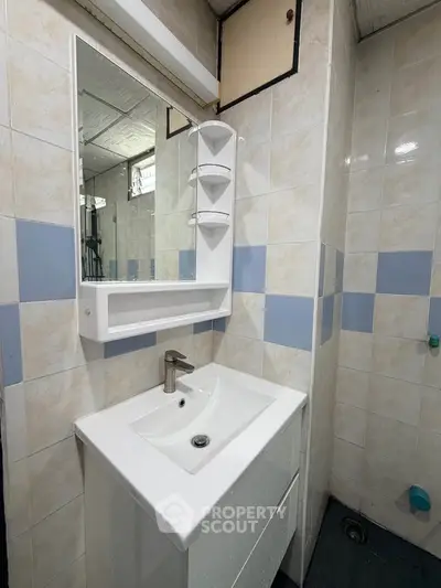 Compact bathroom with modern sink and mirror in tiled setting