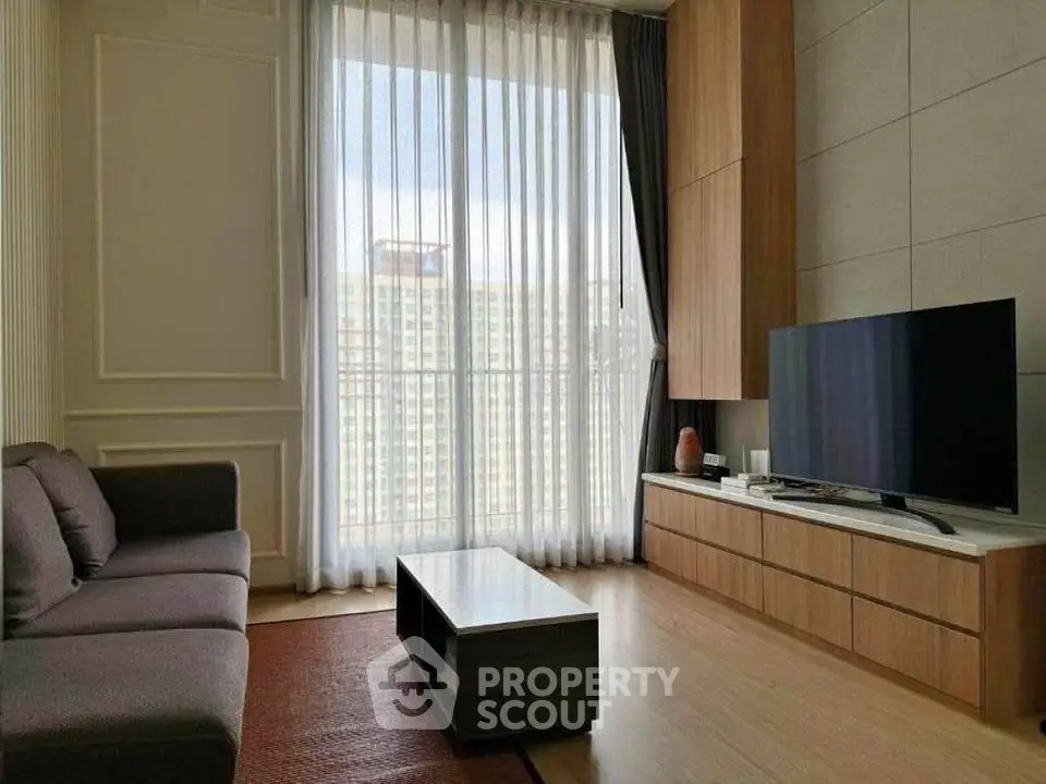 Modern living room with large window and city view, featuring sleek furniture and elegant decor.