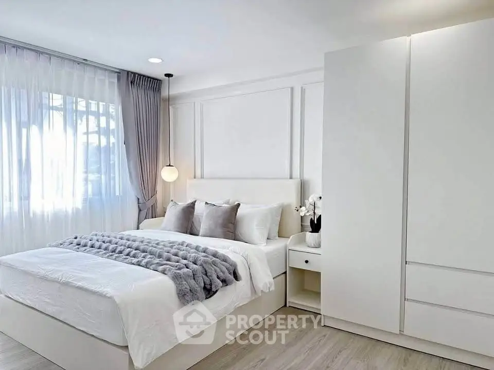 Elegant bedroom with modern decor and ample natural light, featuring a cozy bed and sleek wardrobe.
