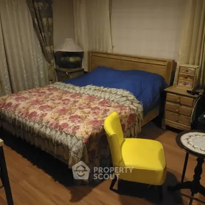 Cozy bedroom with floral bedding and a bright yellow chair, perfect for relaxation.