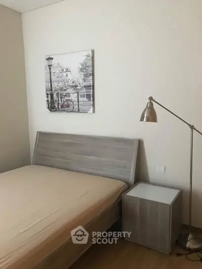 Cozy bedroom with modern decor and stylish lamp, perfect for relaxation.