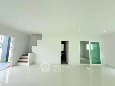 Spacious modern living room with sleek white tiles and staircase, perfect for contemporary living.