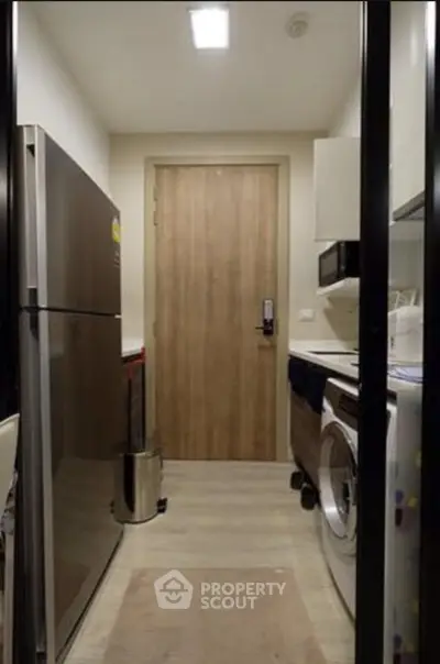 Compact kitchen with modern appliances including fridge and washing machine, sleek design.