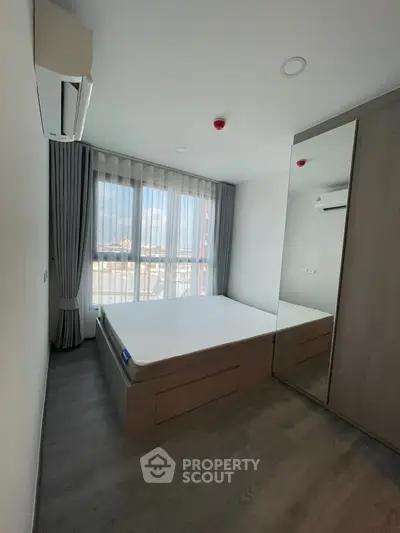 Modern bedroom with large window and mirrored wardrobe in a stylish apartment.