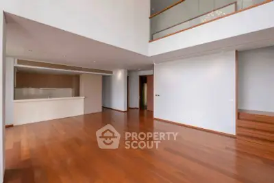 Spacious modern living room with high ceilings and wooden flooring in luxury apartment.