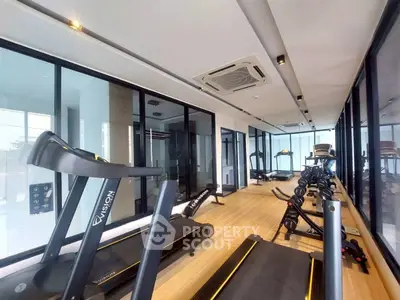 Modern gym with state-of-the-art equipment and floor-to-ceiling windows in luxury building.