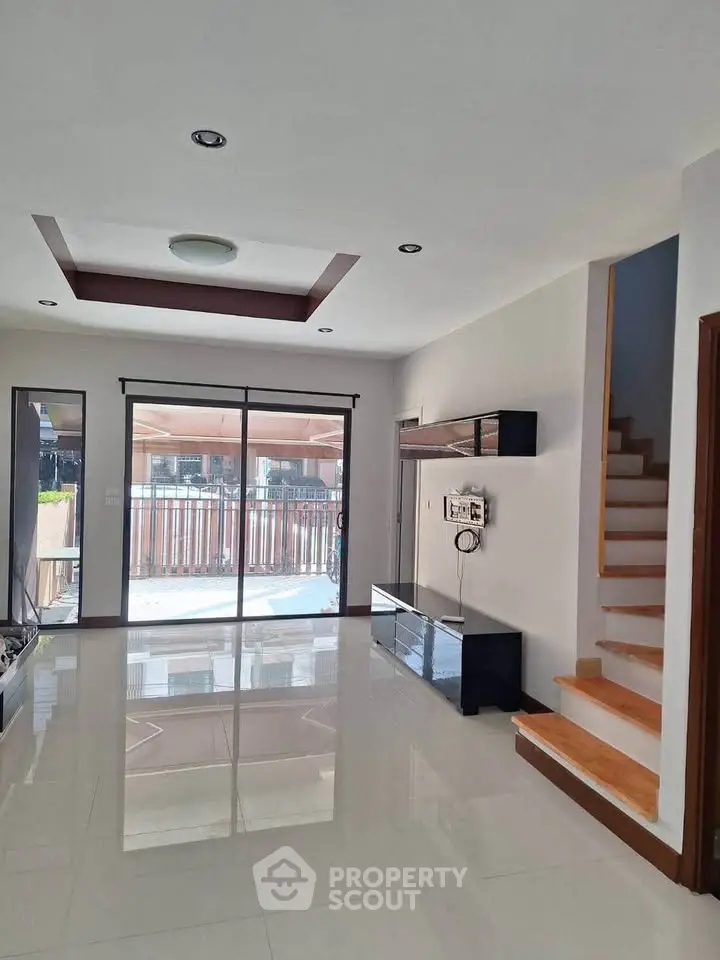 Spacious modern living room with glossy floors and large windows leading to a balcony.