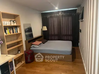Cozy bedroom with wooden flooring, stylish decor, and ample natural light from large window.