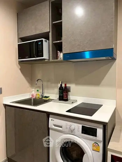 Modern compact kitchen with washing machine and microwave, ideal for urban living.