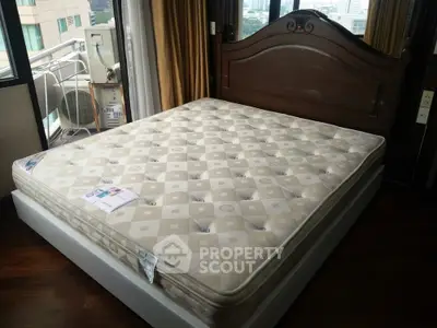 Spacious bedroom with elegant wooden bed frame and large windows offering city views.
