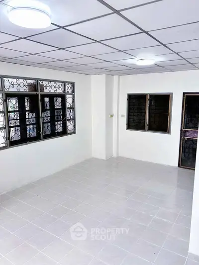 Spacious empty room with tiled floor and large windows for natural light.