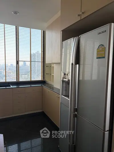Modern kitchen with sleek appliances and city view, featuring a spacious fridge and ample cabinetry.