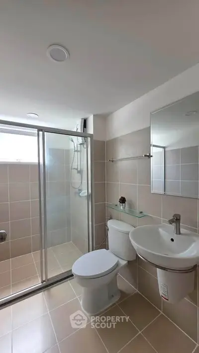 Modern bathroom with glass shower, sleek fixtures, and neutral tiles.