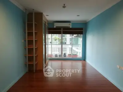 Spacious empty room with wooden flooring and large window, ideal for customization.