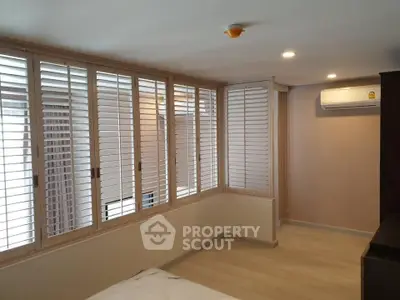 Spacious bedroom with large windows and modern air conditioning unit.