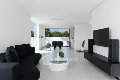 Modern minimalist living room with sleek black furniture and large windows offering natural light.