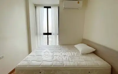 Cozy bedroom with large window and air conditioning unit, perfect for relaxation.