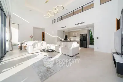 Luxurious open-plan living room with high ceilings and modern decor, featuring elegant lighting and spacious seating area.