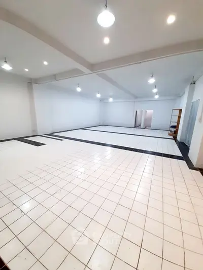 Spacious open-plan interior with tiled flooring and bright lighting, ideal for versatile use.