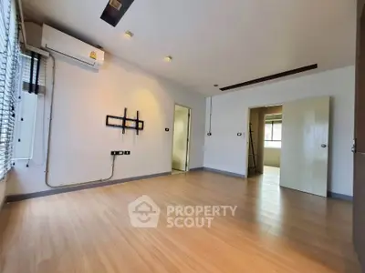 Spacious empty room with wooden flooring and wall-mounted air conditioning, ready for customization.