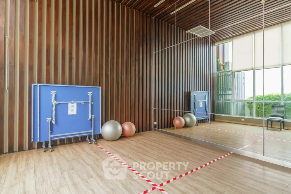 Modern gym with mirrored walls and exercise equipment in luxury apartment complex.
