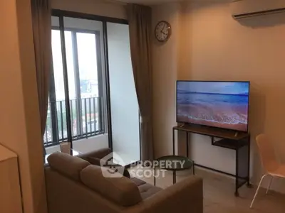 Modern living room with balcony view, featuring a sleek sofa and flat-screen TV, perfect for urban living.