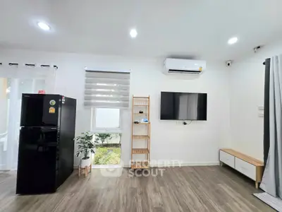 Modern living room with sleek design, featuring a wall-mounted TV, air conditioning, and stylish wooden flooring.