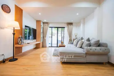 Spacious living room with modern decor and large sofa, featuring wooden flooring and natural light.