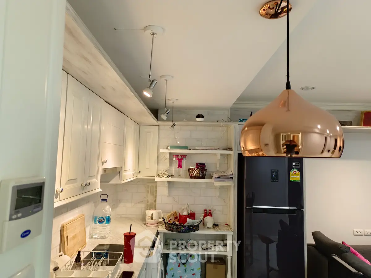 Modern kitchen with sleek appliances and stylish lighting in a cozy apartment setting.