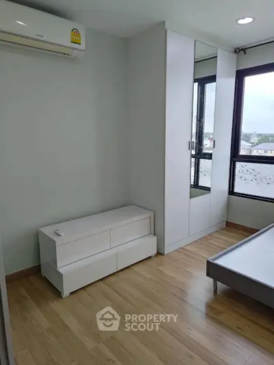 Modern bedroom with sleek furniture and large window offering natural light.